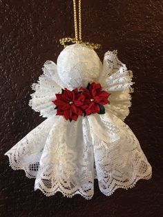 a white angel ornament with red poinsettis hanging from it's side