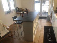 a kitchen island with two stools in front of it and an open door leading to the outside