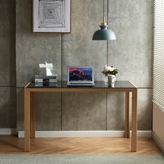 a laptop computer sitting on top of a wooden desk next to a lamp and window