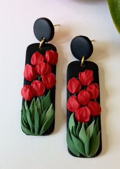 two black and red earrings with flowers painted on the front, one has green leaves