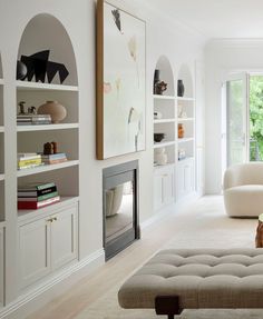 a living room filled with furniture and bookshelves next to a fire place in front of a window