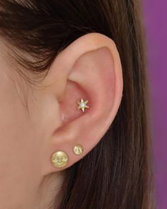 a woman's ear has three small stars on it, and one is gold