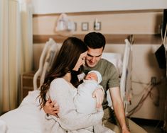 a man and woman holding a baby in a hospital bed