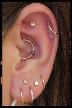 an ear with three different types of piercings on it's side and one is gold