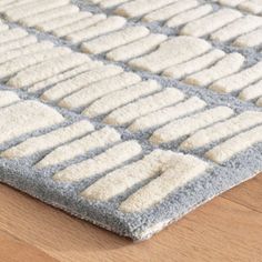 a close up of a rug on a wooden floor with white and gray squares in the middle