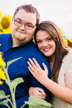 a man and woman hugging in the middle of a sunflower field