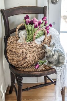 a wicker basket filled with purple tulips sitting on a chair