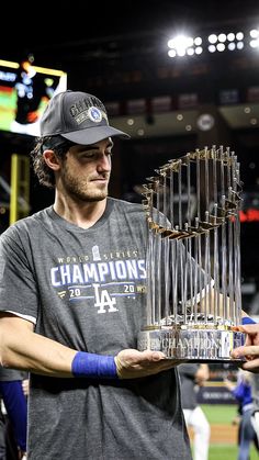 a man holding up a trophy on top of a baseball field