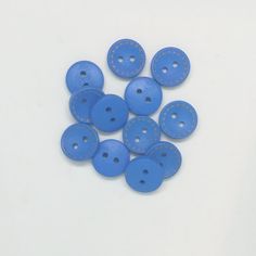 several blue buttons with white stitching are on a white surface and there is no image here to provide a caption for