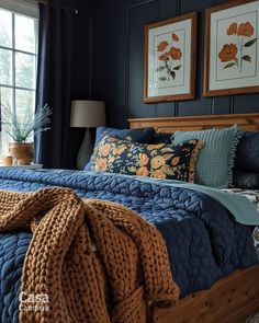 a bed in a bedroom with two framed pictures on the wall above it and a blue blanket