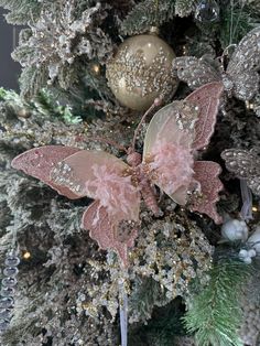 a decorated christmas tree with pink and gold decorations on it's branches in front of a silver ornament