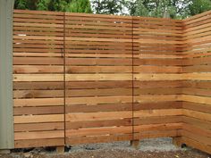 a wooden fence that is next to a tree in the yard with gravel on the ground