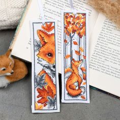 two cross stitch bookmarks with foxes on them