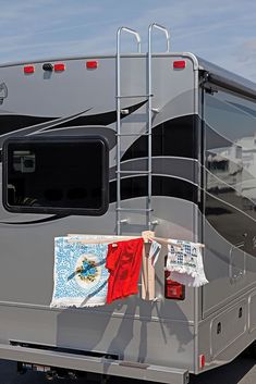 an rv parked in a parking lot with clothes hanging out to dry on the rack