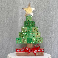 a christmas tree made out of wooden blocks with bows on it and a star hanging from the top