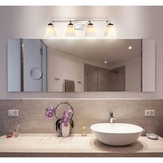 a bathroom with a sink, mirror and lights on the wall above it's counter