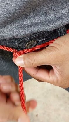 a person tying a red rope around their pants