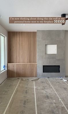 an empty living room with wood slats on the floor and a fireplace in the corner