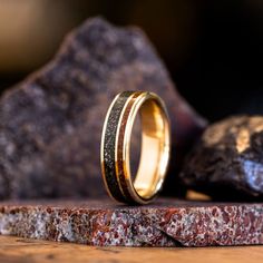 two gold wedding bands sitting on top of a rock