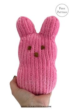 a hand holding a pink knitted bunny mask