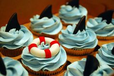 cupcakes with blue frosting and white icing decorated with an life preserver