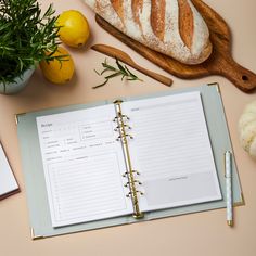 an open recipe book sitting on top of a table next to lemons and bread