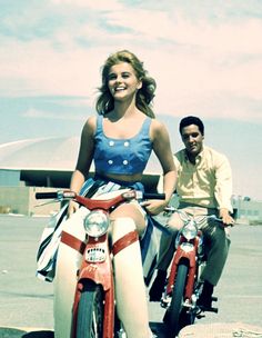 a man and woman riding on the back of motorcycles