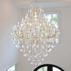 a large chandelier hanging from the ceiling in a room with white walls and windows