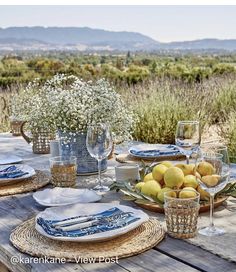 a wooden table topped with plates and glasses filled with lemons on top of it