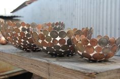 three metal bowls filled with coins sitting on top of a wooden table