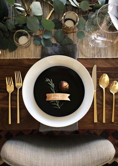 a table setting with black soup and gold utensils, napkins and place settings