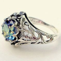 an antique style ring with blue topaz and filigrees on the sides