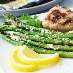 asparagus and chicken on a plate with lemon wedges