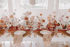 the table is set with flowers and place settings