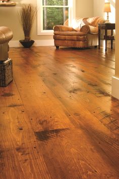 a living room filled with furniture and a brown leather chair next to a wooden floor