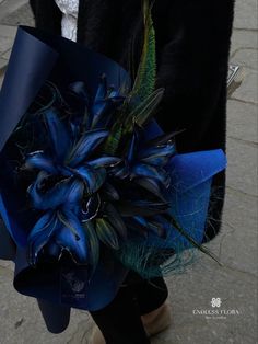 a woman is walking down the street holding a blue bouquet with feathers on it's side