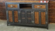 a wooden cabinet with two doors and drawers on the bottom, in front of a wood paneled wall