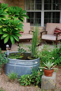 an outdoor garden with a tub and chairs next to it in front of a house