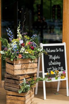 a wooden planter filled with flowers next to a sign