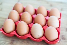 an egg tray filled with brown eggs on top of a wooden table