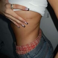 a woman's stomach with the word miss written on her left side and tattoos on her right side