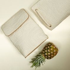 a pineapple sitting on top of a white table next to a piece of leather