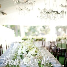 a long table is set with white flowers and green napkins for an elegant wedding reception