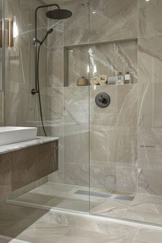 a bathroom with a glass shower door and marble counter top, along with a white sink