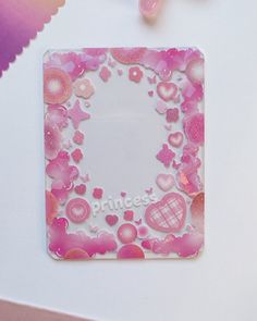 a pink and white photo frame sitting on top of a table next to some candy