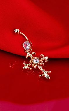 a gold nose piercing with crystal stones on it's end, sitting on top of a red cloth