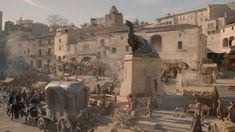 a group of people standing around a statue in the middle of a town with horses and carriages