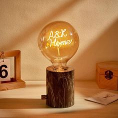 an illuminated light bulb sitting on top of a wooden table next to a clock and other items