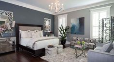 a bedroom with gray walls and white bedding, chandelier, chair, coffee table