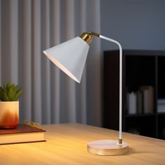 a desk lamp sitting on top of a wooden table next to a potted plant